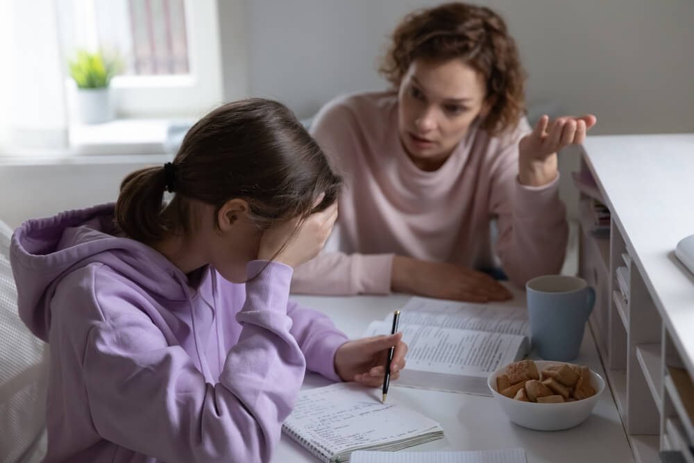 A parent and child at a table during a difficult conversation about schoolwork