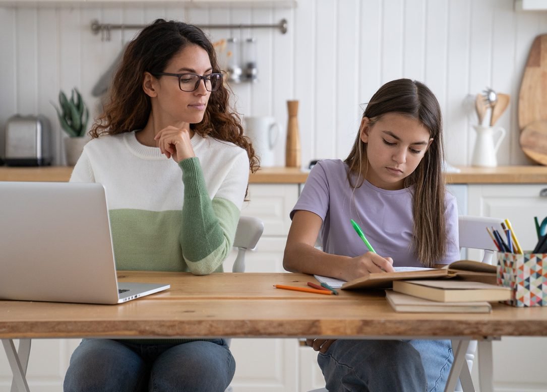 A parent and her daughter working together at the kitchen table